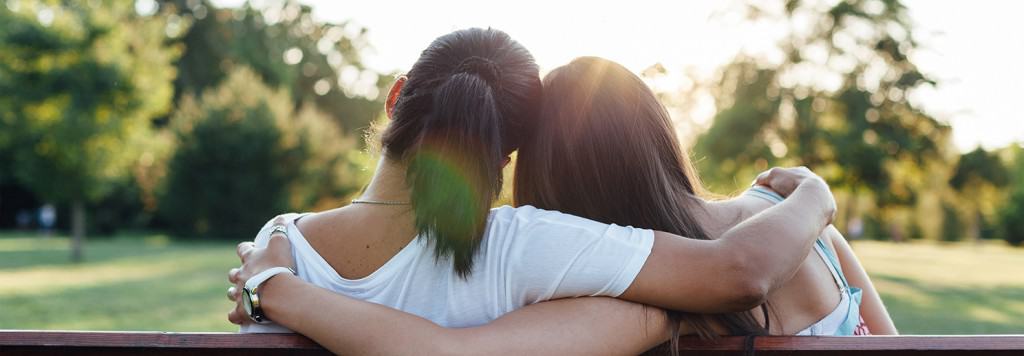 Closeup of mom and daughter embracing on a park bench